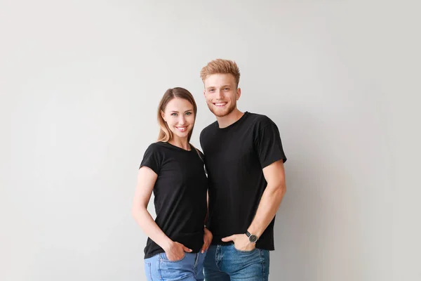 Couple in stylish t-shirts on light background