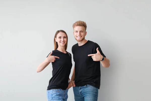 Casal em camisetas elegantes no fundo claro — Fotografia de Stock