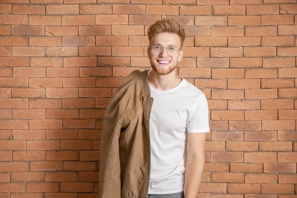 Homem em elegante t-shirt contra parede de tijolo — Fotografia de Stock