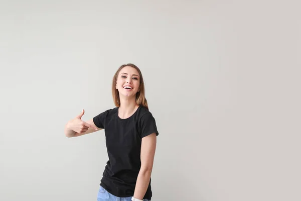 Kadın hafif arka plan karşı onu t-shirt işaret — Stok fotoğraf