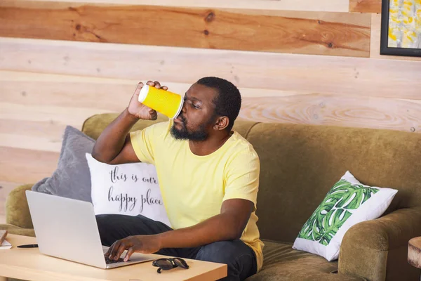 Blogger afroamericano con portátil bebiendo café en la mesa — Foto de Stock