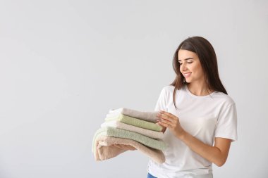 Hafif arka planda temiz havlu yığını ile güzel genç kadın