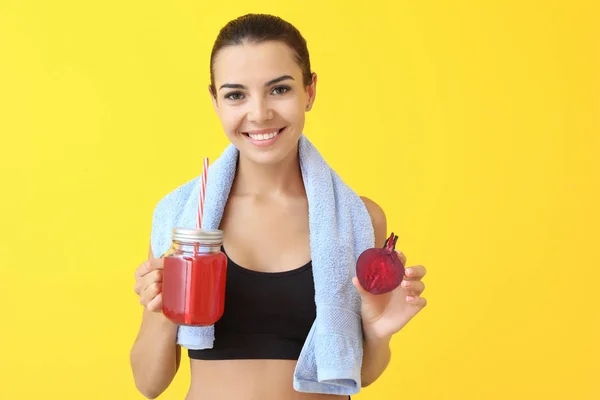 Молодая спортсменка со здоровым свекловичным соком на цветном фоне — стоковое фото