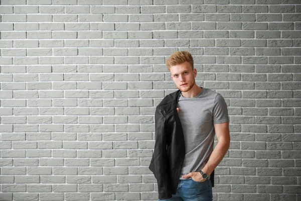 Άνδρας με κομψό t-shirt κοντά στον τοίχο από τούβλα — Φωτογραφία Αρχείου