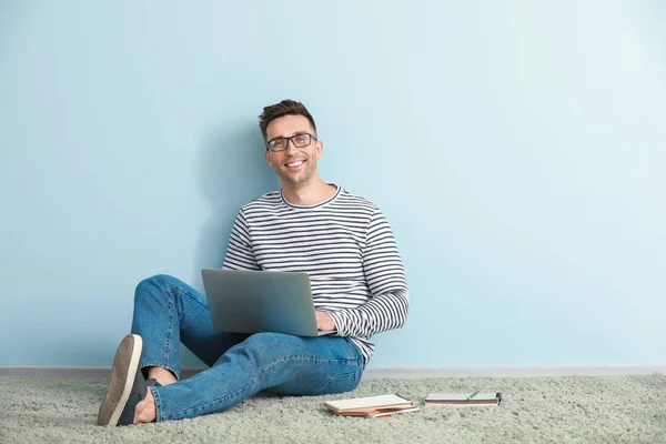 Male blogger with laptop sitting near color wall — Stock Photo, Image