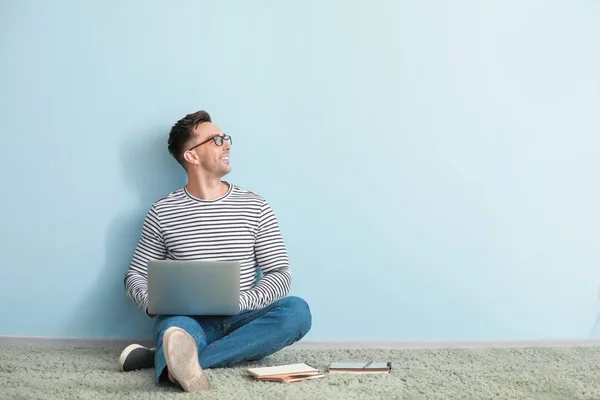 Hombre blogger con portátil sentado cerca de la pared de color — Foto de Stock