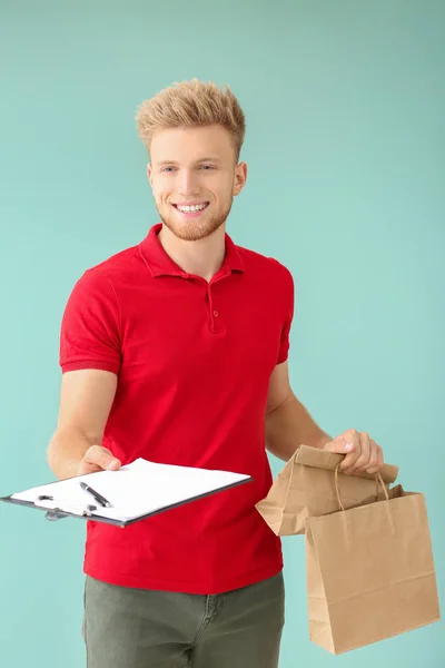 Handsome worker of food delivery service on color background — Stock Photo, Image