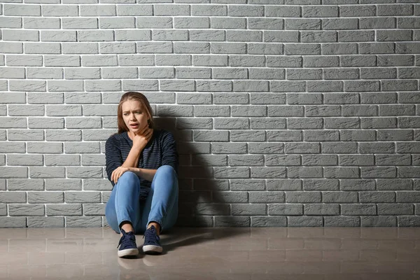 Donna che ha un attacco di panico mentre seduto vicino al muro di mattoni — Foto Stock