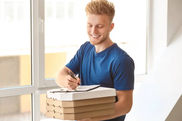 Worker of food delivery service with pizza indoors — Stock Photo, Image