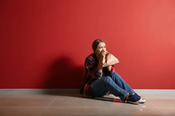 Woman having panic attack while sitting near color wall — Stock Photo, Image