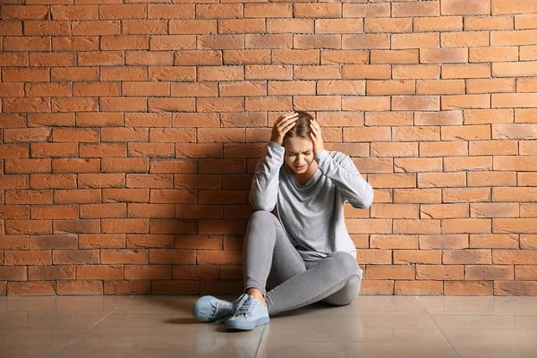 Mujer teniendo ataque de pánico mientras está sentado cerca de la pared de ladrillo —  Fotos de Stock