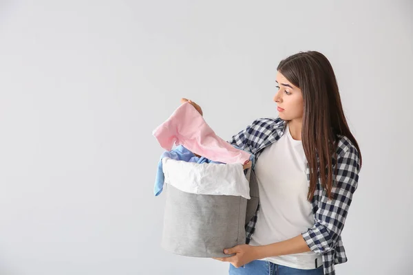Beautiful young woman with laundry on light background — Stock Photo, Image