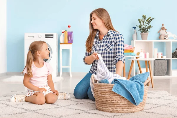 女性と彼女の小さな娘は、自宅で洗濯をしています — ストック写真