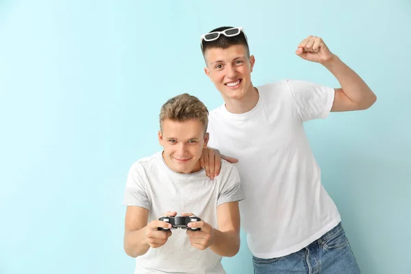 Teenagers playing video game on color background — Stock Photo, Image