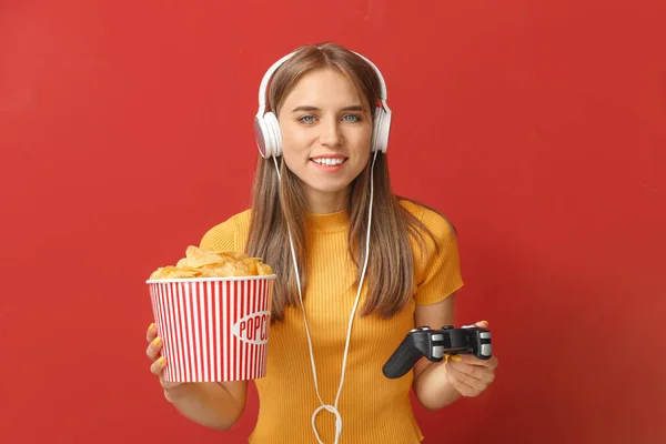 Ragazza adolescente con popcorn giocare video gioco su sfondo di colore — Foto Stock