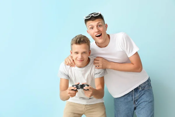 Teenagers playing video game on color background — Stock Photo, Image