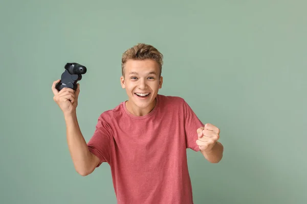 Menino adolescente feliz jogando jogo de vídeo no fundo de cor — Fotografia de Stock