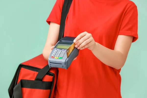 Mitarbeiterin des Essenslieferdienstes mit Zahlungsterminal auf farbigem Hintergrund — Stockfoto