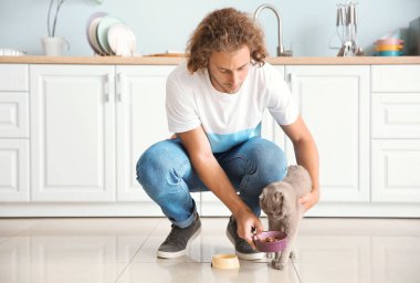 Adam mutfakta sevimli komik kedi besleme