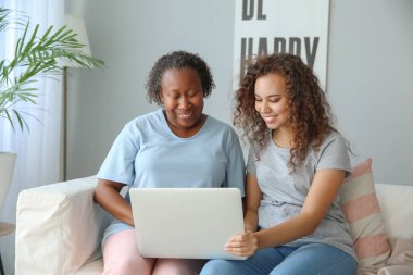Evde dizüstü bilgisayar ile Afrikalı-Amerikalı kadın ve kızı Portresi