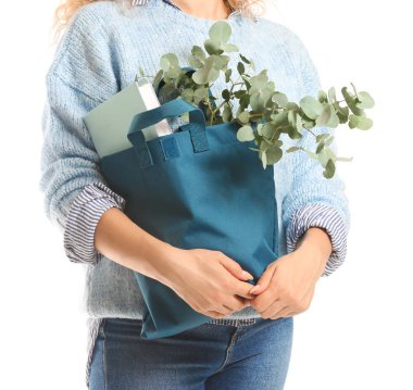 Beyaz arka plan üzerinde eko çanta içinde kitap ve okaliptüs ile Kadın, closeup