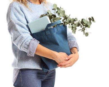 Beyaz arka plan üzerinde eko çanta içinde kitap ve okaliptüs ile Kadın, closeup