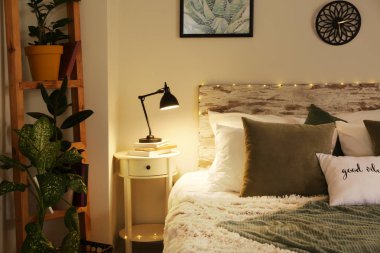 Odanın şık iç lamba ve bitkiler ile büyük rahat yatak ve masa