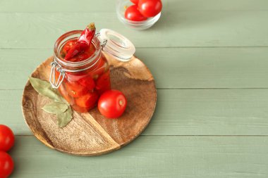 Ahşap masada konserve domates ve biber ile Kavanoz