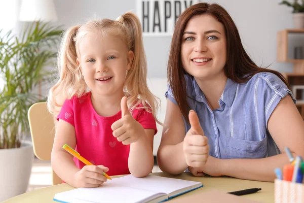 Madre aiutare la sua piccola figlia a fare lezioni a casa — Foto Stock