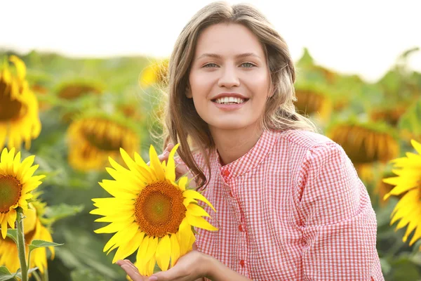 Beautiful young woman in sunflower field on summer day — Stock Photo, Image