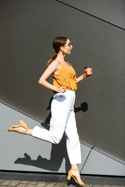 Correndo jovem mulher com xícara de café ao ar livre — Fotografia de Stock