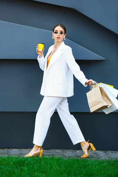 Going fiatal nő, bevásárló táskák és csésze kávét a szabadban — Stock Fotó