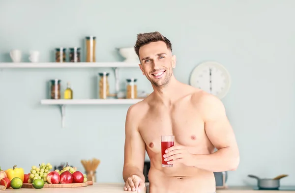 Handsome muscular man drinking juice in kitchen. Weight loss concept — Stock Photo, Image