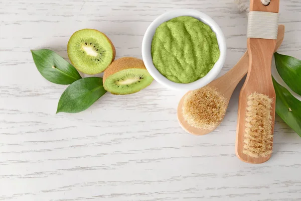 Esfregue com kiwi e escovas na mesa de madeira branca — Fotografia de Stock