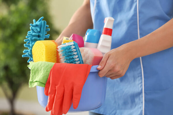 Уборщица с чистящими средствами в номере, крупным планом
