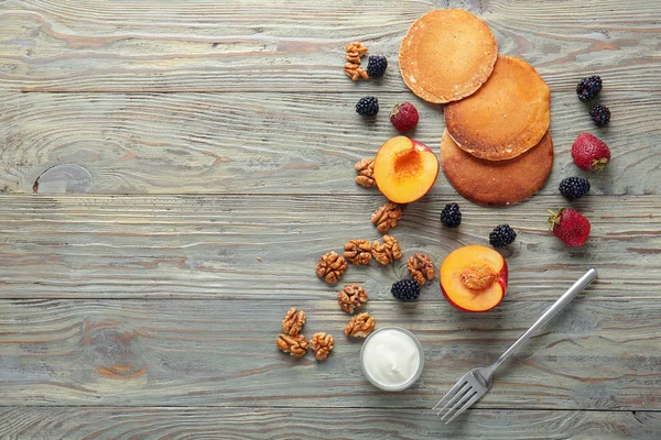 Tasty pancakes with fruits, sauce and walnut on wooden table — Stock Photo, Image