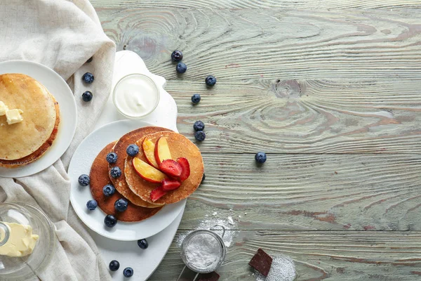 Leckere Pfannkuchen mit Beeren und Butter auf Holztisch — Stockfoto