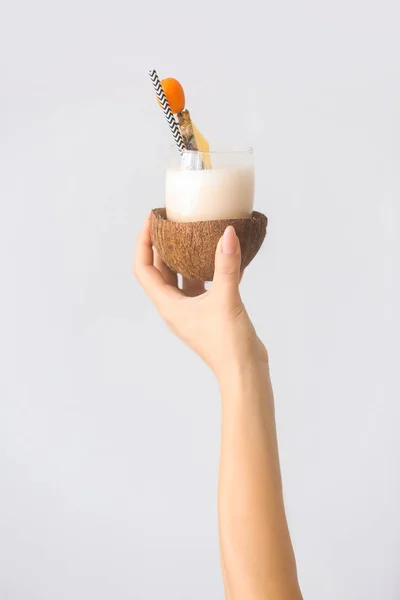 Mano femminile con gustoso cocktail Pina Colada su sfondo chiaro — Foto Stock