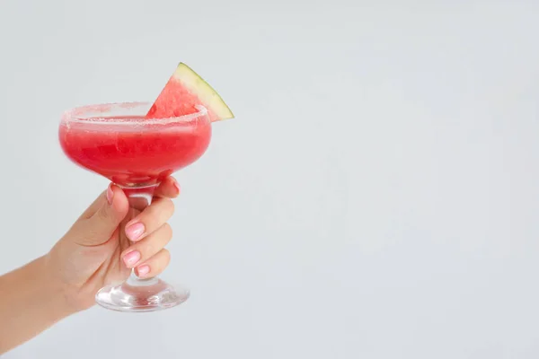 Weibliche Hand mit einem Glas frischem Wassermelonensaft auf hellem Hintergrund — Stockfoto