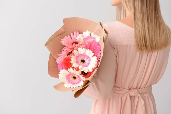 Woman with bouquet of beautiful gerbera flowers on light background — Stock Photo, Image