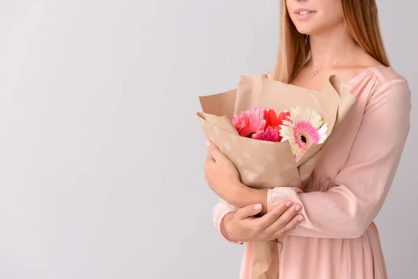 Woman with bouquet of beautiful gerbera flowers on light background — Stock Photo, Image