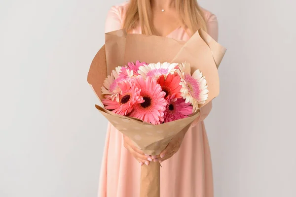 Woman with bouquet of beautiful gerbera flowers on light background — Stock Photo, Image