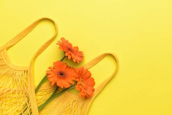 Bag with beautiful gerbera flowers on color background — Stock Photo, Image