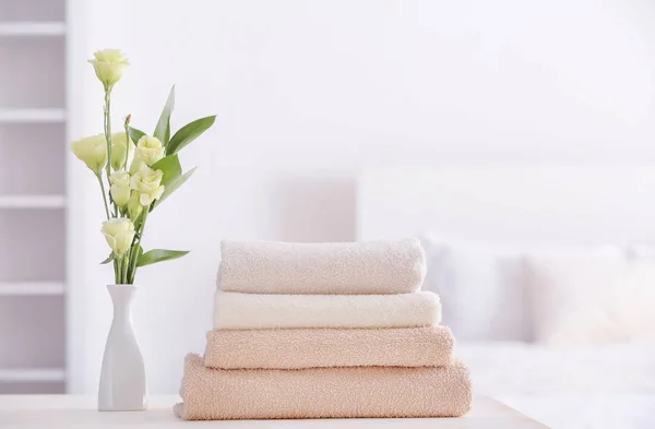 Stack of clean towels on table in bedroom — Stock Photo, Image