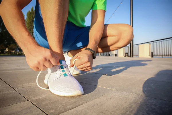Handsome sporty man tying shoelaces outdoors — Stock Photo, Image