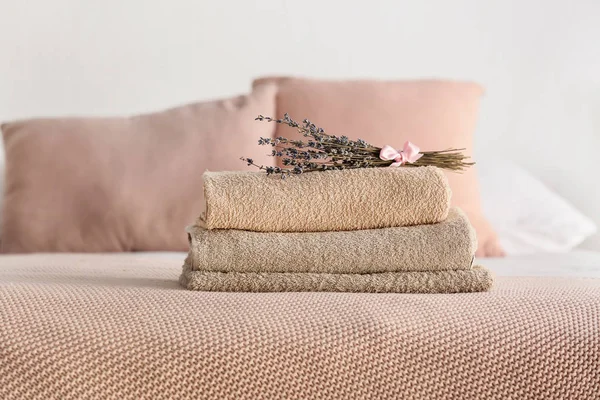 Stack of clean towels with lavender flowers on bed — Stock Photo, Image