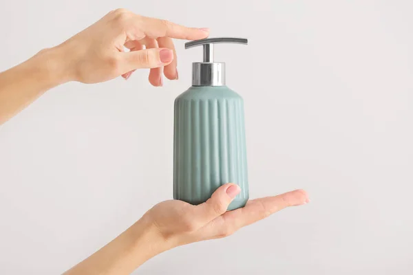 Γυναικεία χέρια με σαπούνι σε μπουκάλι σε ανοιχτόχρωμο φόντο — Φωτογραφία Αρχείου