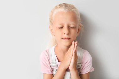 Küçük kız ışık arka plan üzerinde dua