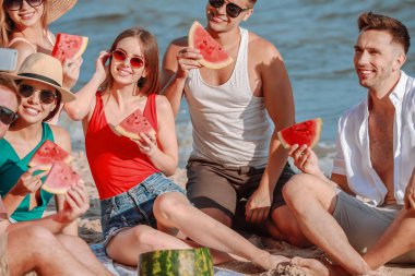 Tatil beldesinde deniz plajında karpuz yerken selfie çeken mutlu arkadaşlar