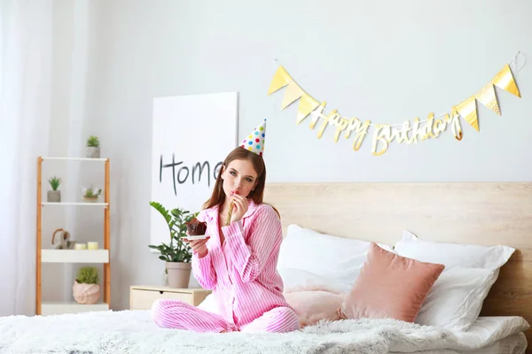 Mujer feliz con pastel de cumpleaños y silbato de fiesta en el dormitorio en casa —  Fotos de Stock